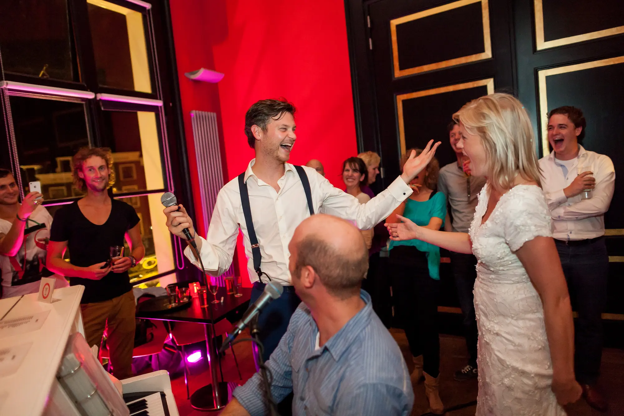 Bruidspaar zingt en lachen samen tijdens interactief live piano-entertainment op een bruiloft